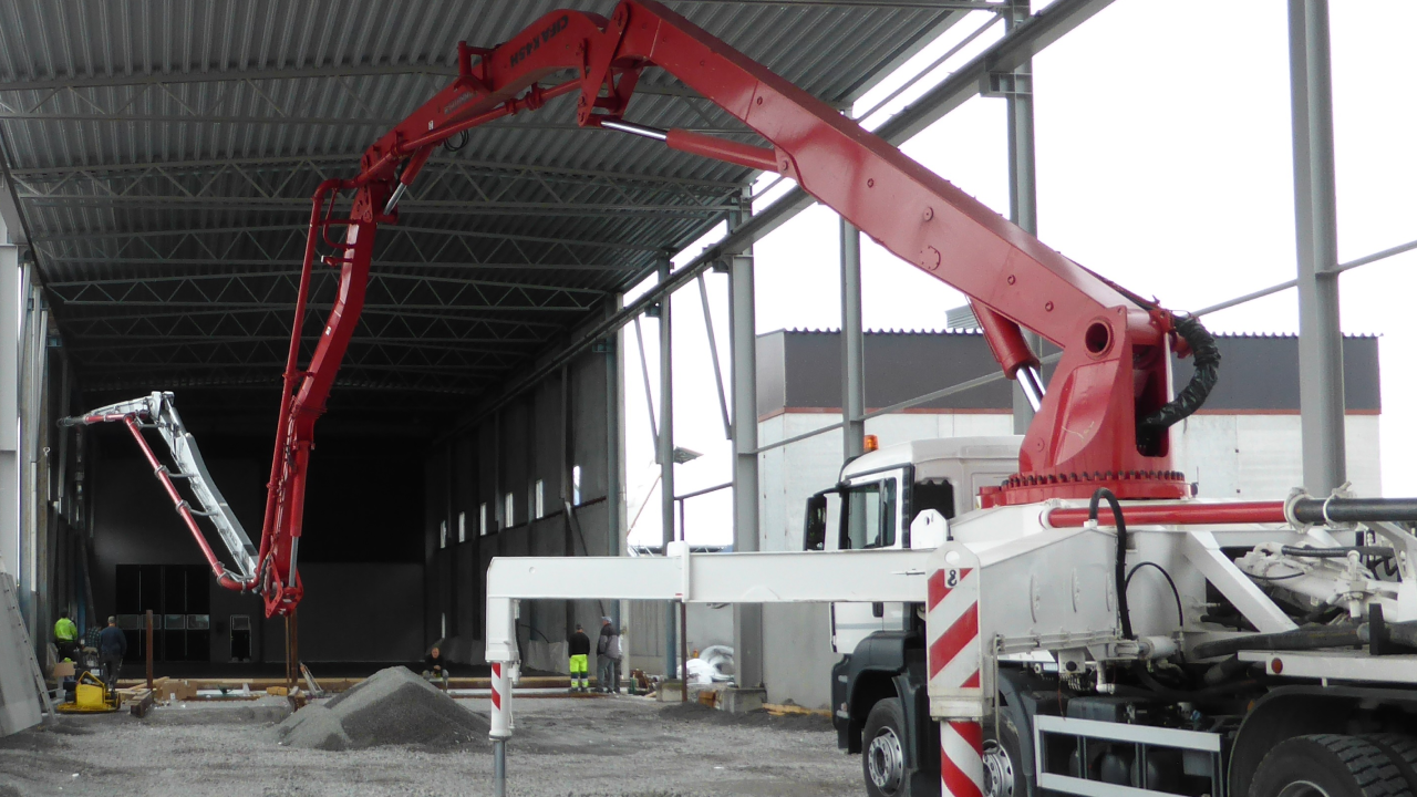 A concrete pumping truck with its arm outstretched.