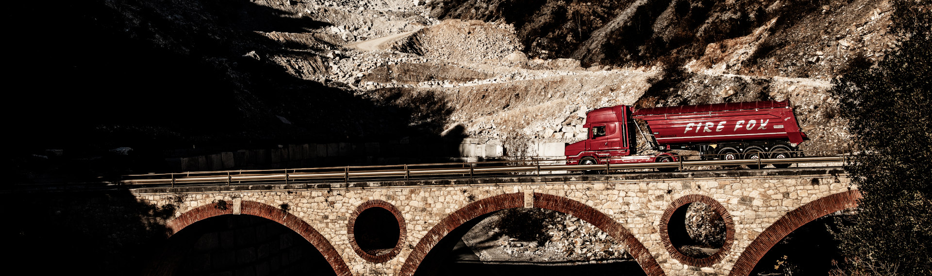 A fiery red Fire Fox truck, made in Hardox 500 Tuf steel plate, crossing a bridge