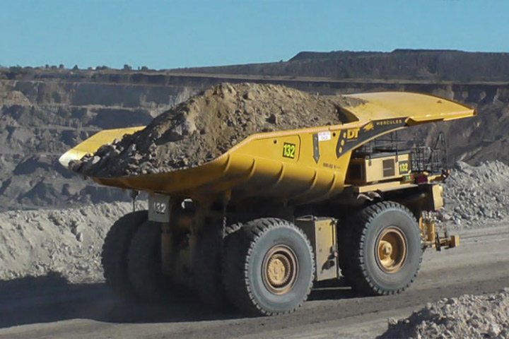 A yellow mining haul truck on the road carrying dirt and rocks