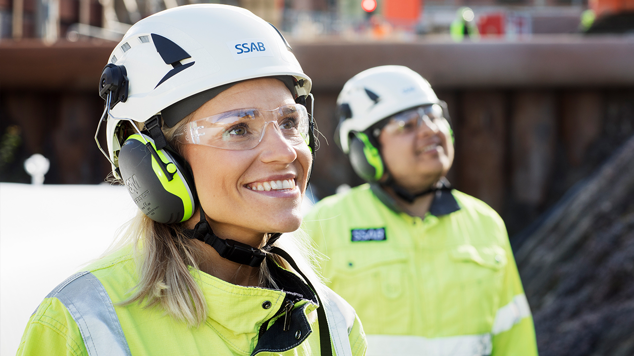Two smiling SSAB employees wearing hard hats.